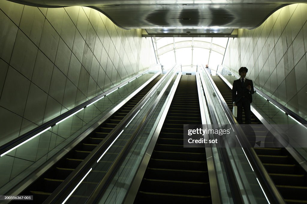 Businessman descending escalator