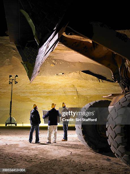 construction workers looking at plans in sand mine at night - baustelle bagger stock-fotos und bilder