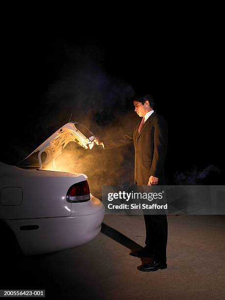 businessman looking into glowing trunk of car - car trunk stock pictures, royalty-free photos & images