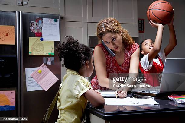 mother and two daughters (8-12) in kitchen - multitarefas imagens e fotografias de stock
