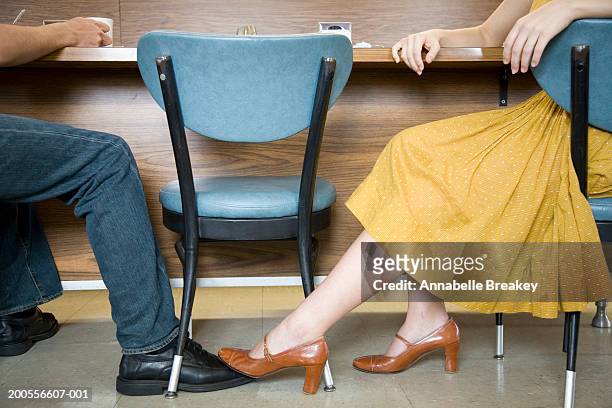 couple sitting in cafe, woman playing footsie with man - playing footsie - fotografias e filmes do acervo