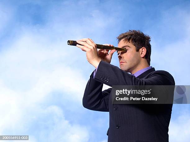 young businessman looking through antique telescope - 望遠鏡　男性 ストックフォトと画像