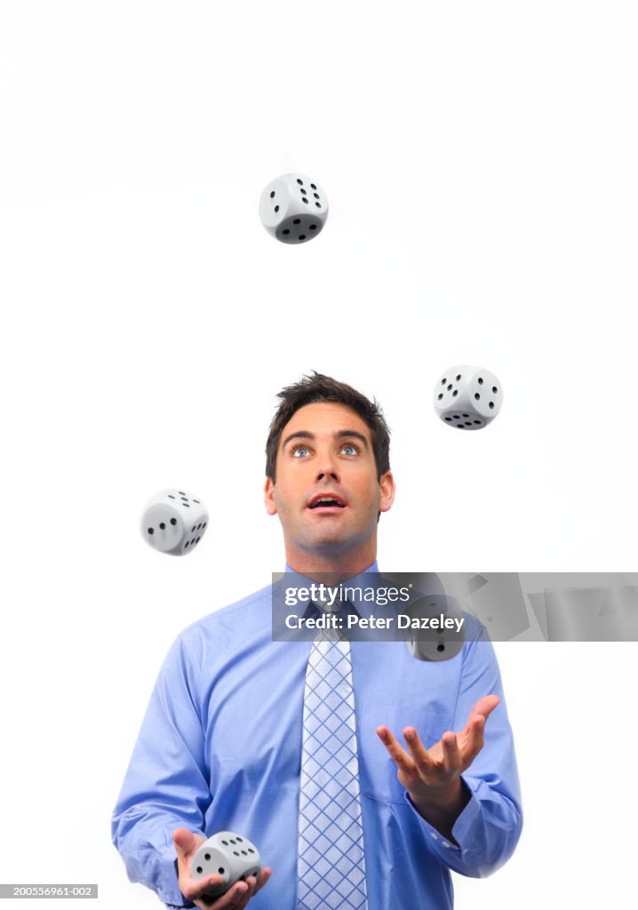 Young businessman juggling dice on white background