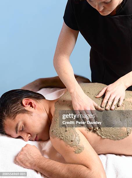 man having massage with mud given by female masseur - fango stock-fotos und bilder