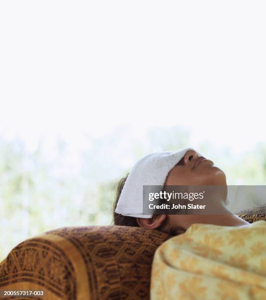 young woman resting with towel over eyes - covering eyes stockfoto's en -beelden