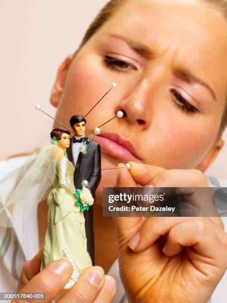 young woman sticking pins in bride and groom figurines - vingança imagens e fotografias de stock