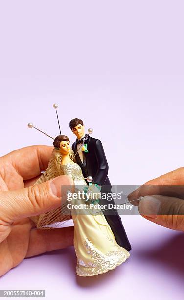 young woman sticking pins in bride and groom figurines, close-up - voodoo doll stock pictures, royalty-free photos & images