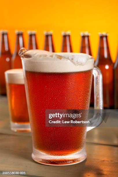 pitcher of beer, beer bottles in background - jug stock pictures, royalty-free photos & images