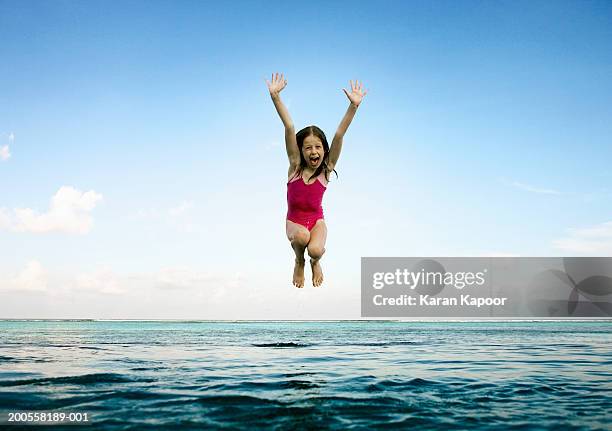 girl (8-9) jumping into infinity pool, mouth open - maldives sport foto e immagini stock
