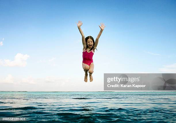 girl (8-9) jumping into infinity pool, mouth open - jumping in pool stock pictures, royalty-free photos & images