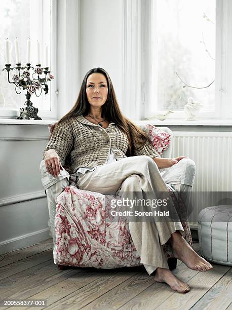 mature woman sitting in armchair, portrait - armstoel stockfoto's en -beelden