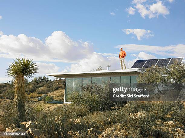 man standing atop roof of prefabricated home with solar panels - solar panel isolated stock pictures, royalty-free photos & images