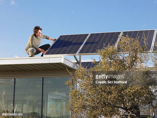 man installing solar panels  atop prefabricated home - roof installation stock pictures, royalty-free photos & images