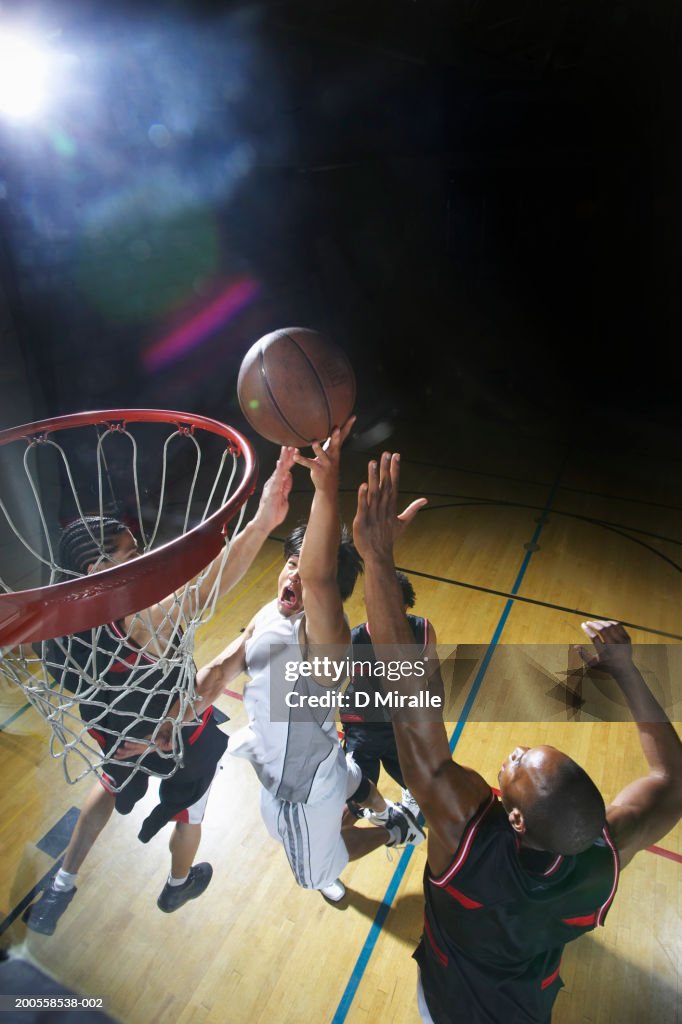 Basketball player doing lay-up against defenders