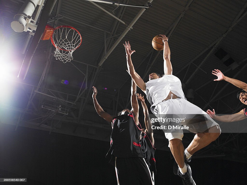 Basketball player playing agianst defenders, low angle view