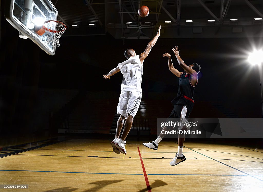 Basketball player shooting fade away while opponent blocks shot