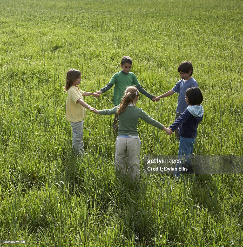 Children (6-9) holding hands in circle