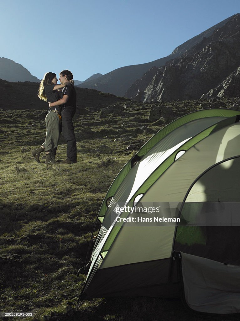 Couple embracing on mountain by tent