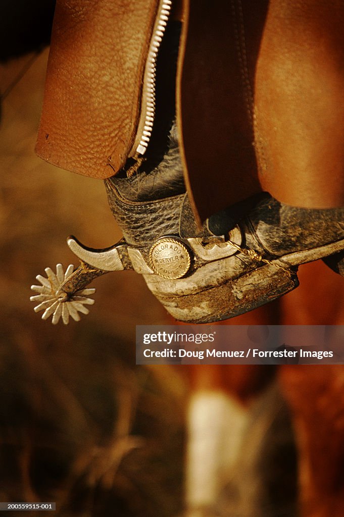 Man with cowboy boots riding horse, close-up
