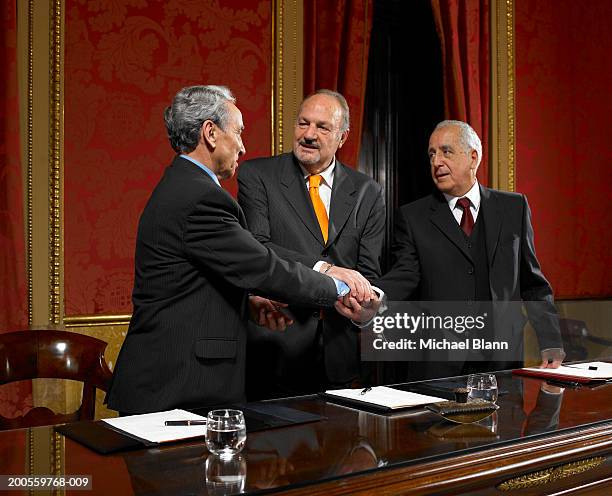 three politicians shaking hands at conference table, smiling - uomo politico foto e immagini stock