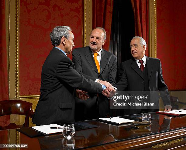 three politicians shaking hands at conference table, smiling - politician meeting stock pictures, royalty-free photos & images