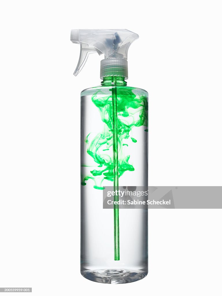 Spray bottle with water and green liquid, close-up