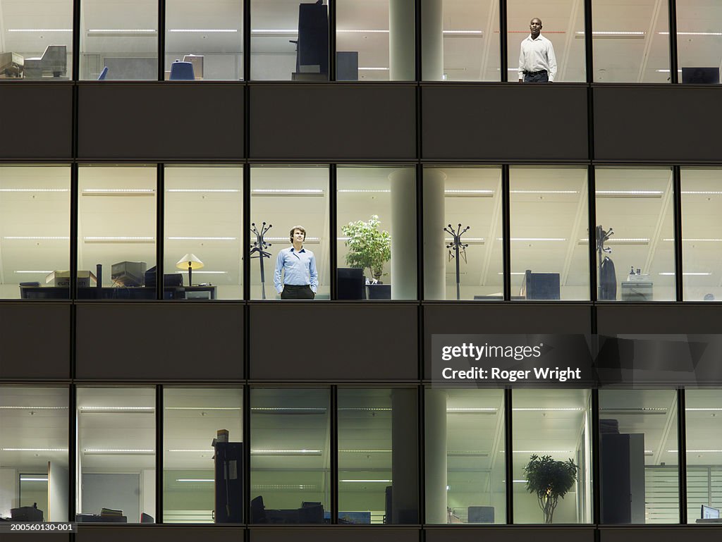 Illuminated office building with workers at window