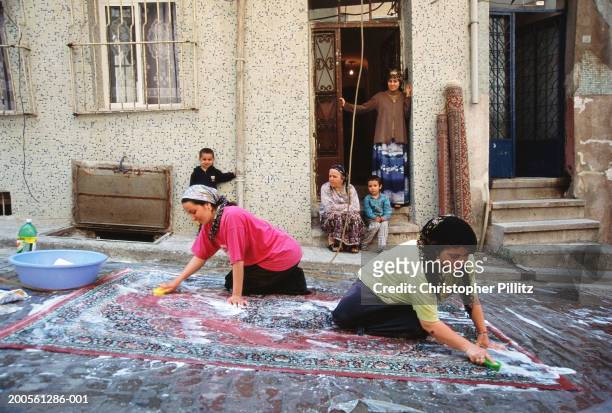 Turkey, Istanbul, Balat, women washing carpets in street.