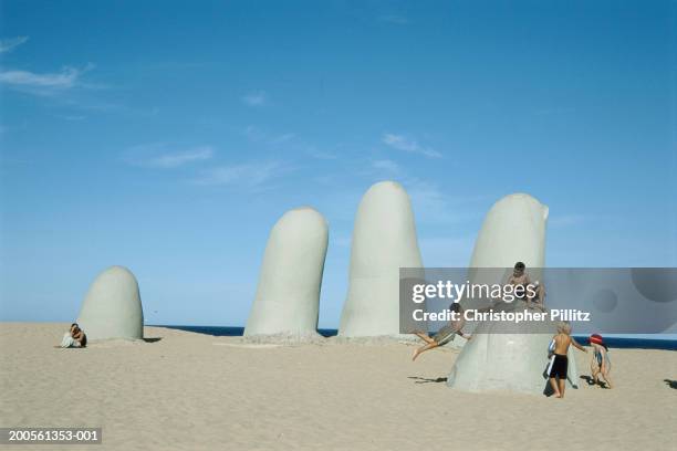 Uruguay, Punta del Este, children playing on sculpture on Brava beach.