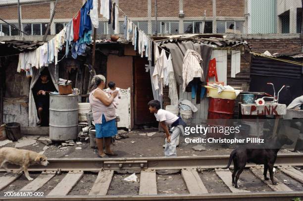 Mexico Woman, Mexico City, children and dogs in slum next to train tracks.