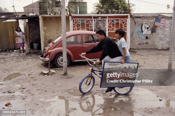 Mexico, Mexico City, man and boy on bicycle in slum.