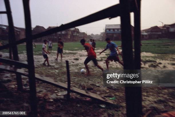 Peru, Iquitos, boys playing football in muddy street.