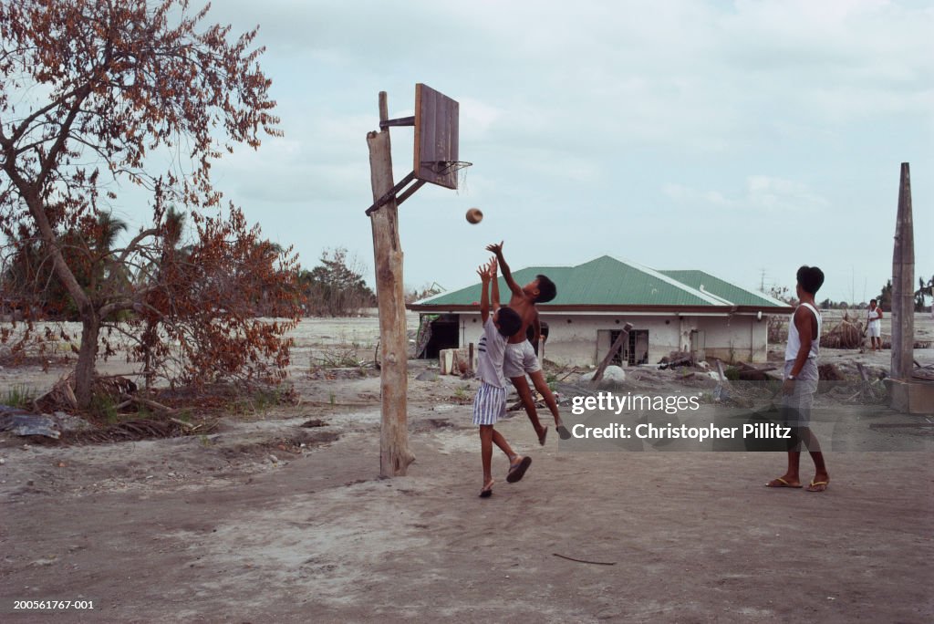 Philippines, boys playing basketball amidst ruins of Santa Rita town