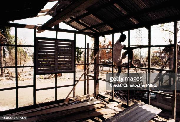 Philippines. Rebuilding homes close to Mt. Pinatubo. Person climbing house construction frame.
