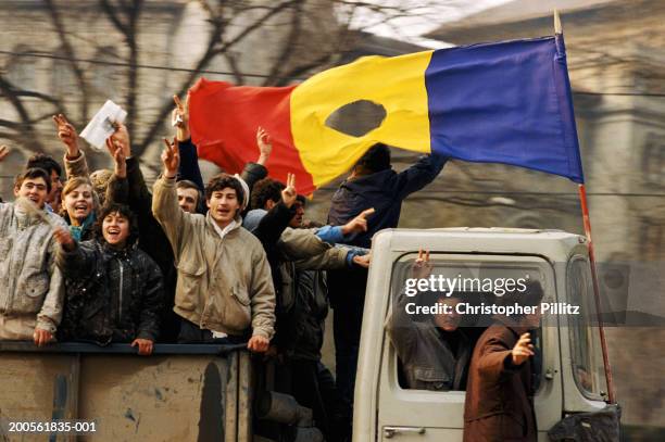 Romanians celebrate after putting end to Ceausescu's reign. Romania, people celebrating on truck with national flag.