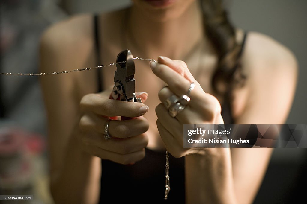 Female jeweller cutting chain with pincers, close-up