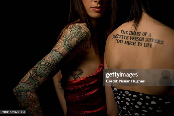 two young women with tattoo on arm and back - back tattoo stock pictures, royalty-free photos & images