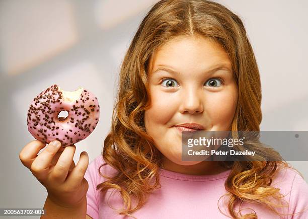 overweight girl (8-9) eating doughnut, smiling, portrait, close-up - fat imagens e fotografias de stock