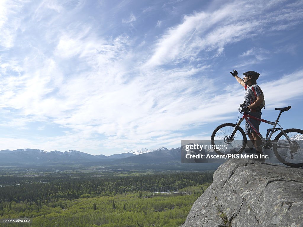 Mountain biker on top of rock with mountain bike, side view