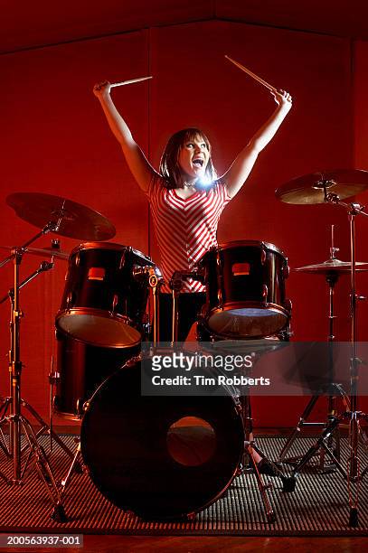 young woman playing drums, holding drumsticks high up, yelling - ドラム ストックフォトと画像