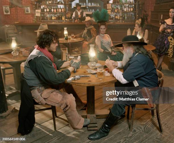 two men playing cards with showgirls beside them at bar - saloon photos et images de collection