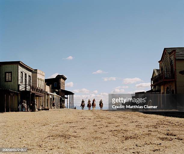 cowboys riding horses through town - old west town stock pictures, royalty-free photos & images