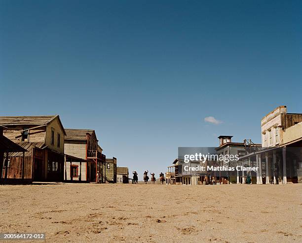 cowboys riding horses through town - ouest américain photos et images de collection
