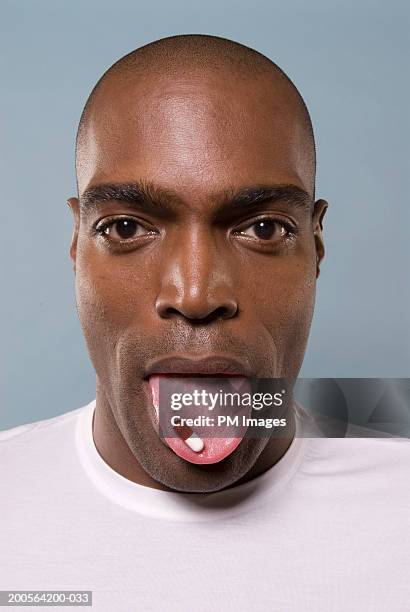 man with capsule on tongue, portrait, close-up - human tongue stock-fotos und bilder