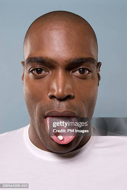 man with capsule on tongue, portrait, close-up - mensentong stockfoto's en -beelden