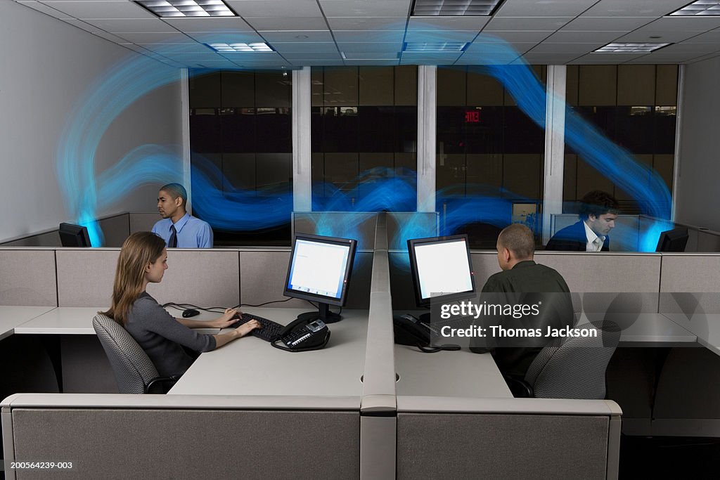 Businesspeople in cubicles,computers connected by stream of blue light