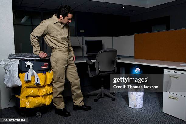 janitor in office, surprised by glowing paper rising from wastebasket - wastepaper basket stock pictures, royalty-free photos & images