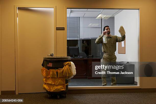 janitor in office late at night, cleaning window - hausmeister stock-fotos und bilder