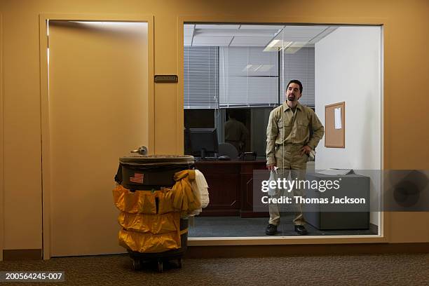 janitor in office late at night, cleaning window - cleaner man uniform stock-fotos und bilder