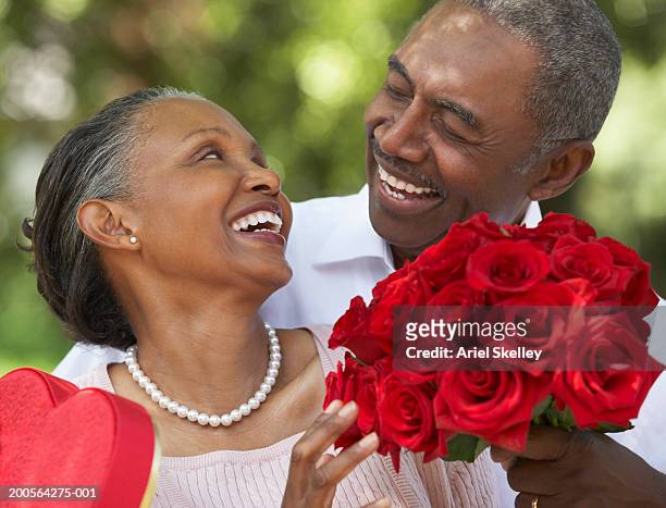 senior man giving box of chocolates and bunch of roses to woman - valentines african american 個照片及圖片檔